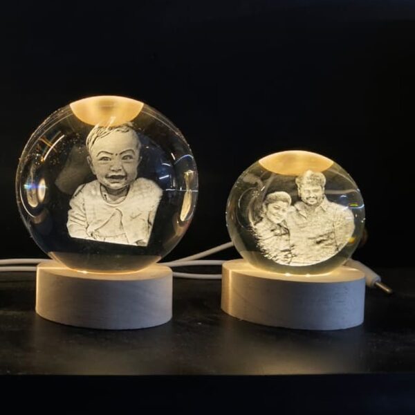 Personalized 3D crystal ball lamps with a baby photo and a couple photo engraved inside, glowing on LED wooden bases